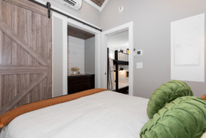 the bedroom of this tiny house comes with built in storage such as a dresser.