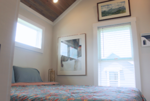 Tiny home bedroom with windows and high sloped ceiling.