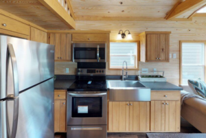 Echoe tiny home kitchen with stainless steel farmhouse sink and appliances.
