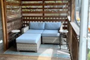 Screened in front porch with furniture and privacy wall.