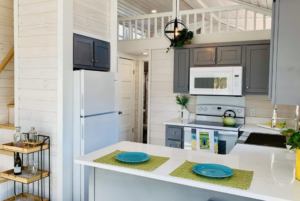 Horseshoe tiny home kitchen with gray cabinets.
