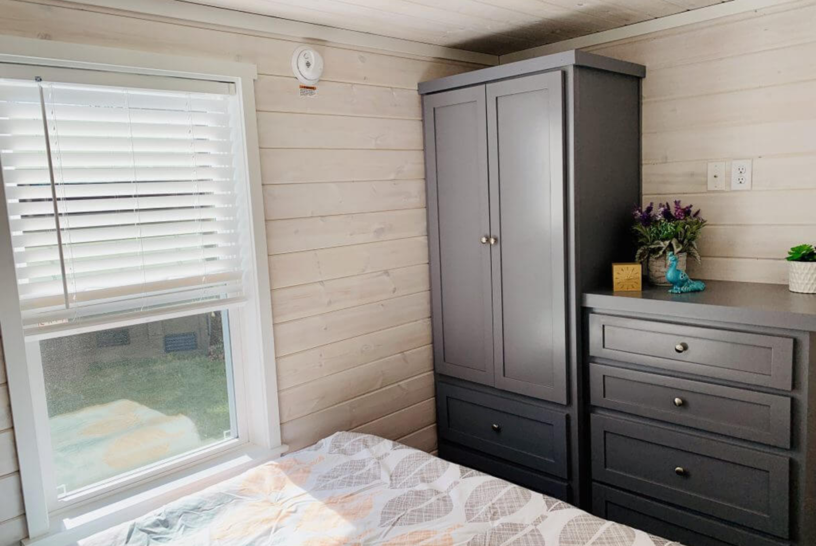 Horseshoe tiny home bedroom with built-in wardrobe and dresser.