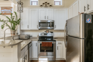 Light kitchen with modern stainless steel oven, microwave, and fridge.