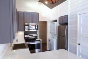 Modern tiny home kitchen with stainless steel appliances and plenty of storage.