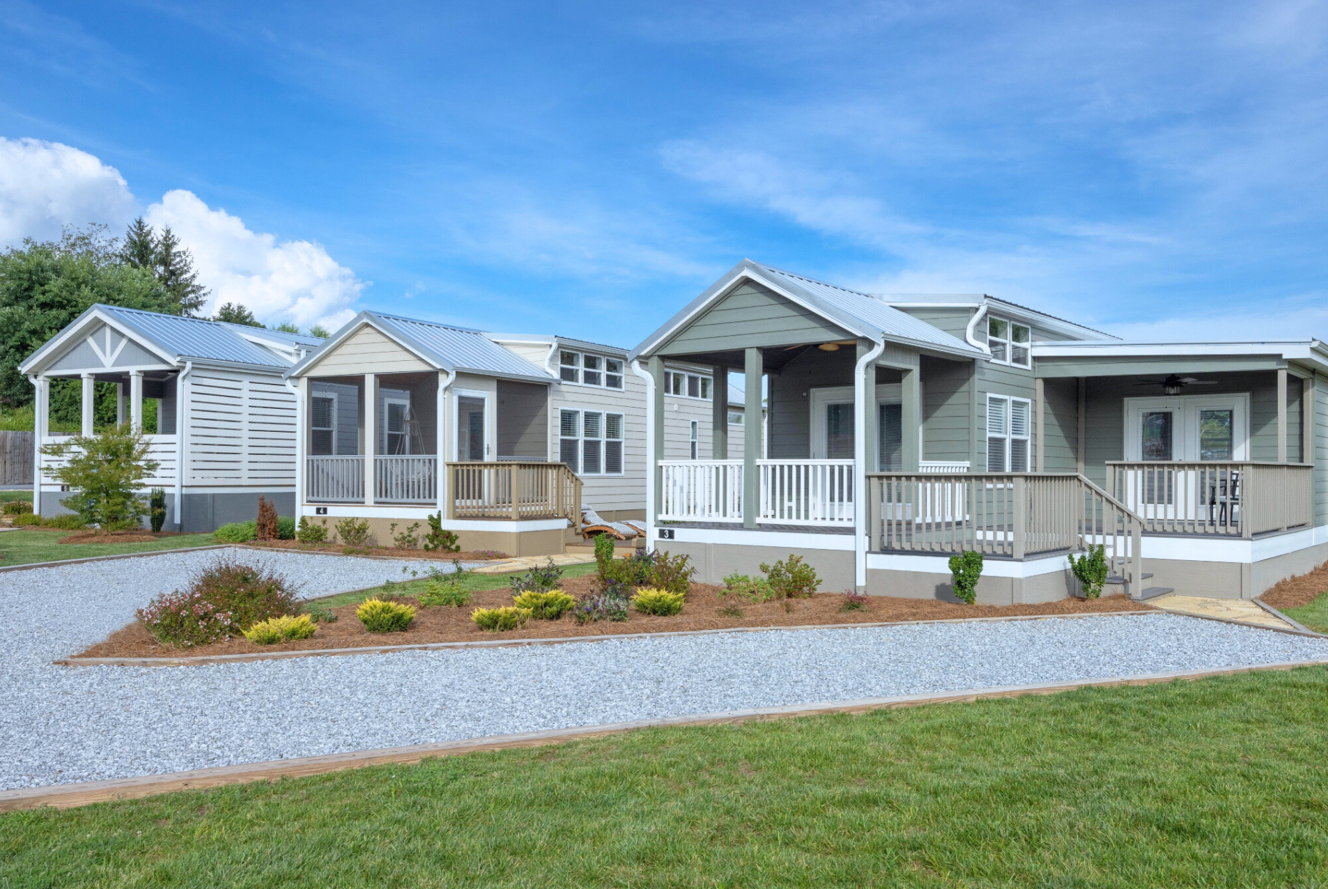 Modern modular homes in a residential area with landscaped yards under a clear blue sky.