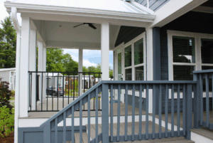Blue and white front porch with stairs, black railing, and ceiling fan, leading to a modern 2 Beds swayback house.