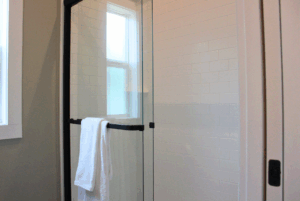 Glass shower with black frame and white towel, next to window with natural light in 2 beds swayback suite.