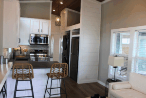 Modern kitchen with stainless steel appliances, bar seating, and natural light in this stylish 2 Beds Swayback home.