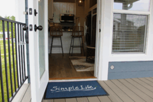 A blue doormat reading Simple Life at the entrance of a swayback home with an open door.