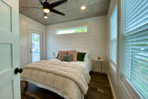 bedroom in a tiny house with a ceiling fan, and door leading to outdoor deck