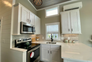 U shaped kitchen with windows and white quartz countertops.