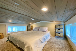 Loft in tiny home with windows can be used as a guest sleeping area, extra storage and more.