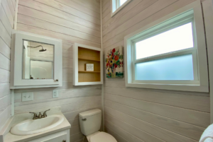 Bathroom in tiny home with multiple windows.