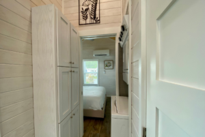 tiny home model with built-in storage in hallway and stackable washer and dryer.