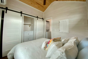 Bedroom in tiny home with large storage space. Built-in dresser and closet with barn doors.