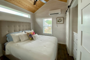 bedroom in tiny house with large bed and buil-in storage.