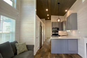 Open floorplan layout in tiny home with kitchen breakfast counter and storage overhead