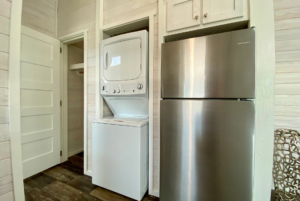 tiny home includes appliances such as refrigerator and stackable washer and dryer