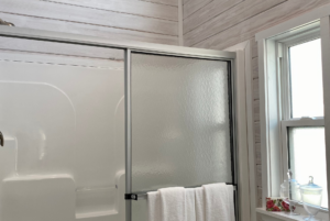 Walk in shower in tiny home bathroom with a nice window allowing for natural light.
