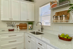 Quartz kitchen sounters with white cabinets and large window