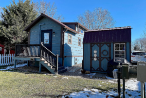 View of tiny home from backyard with shed