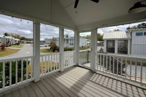 View from a covered porch overlooking Strolling Easy Lane’s small white mobile homes on a cloudy day.