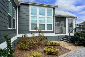 Modern gray house on Strolling Easy Lane with large windows, a small garden, and a screened porch with steps.