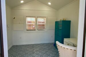Small, bright home office at 40 Drifting Brook Lane with teal cabinet, white desk, and patterned floor.