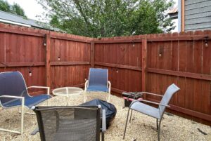 Outdoor patio at 40 Drifting Brook Lane with chairs, table, string lights, fire pit, and fenced gravel area—perfect real estate find.