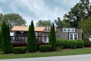 Charming small house at 40 Drifting Brook Lane with a metal roof, front porch, and lush yard under a cloudy sky.