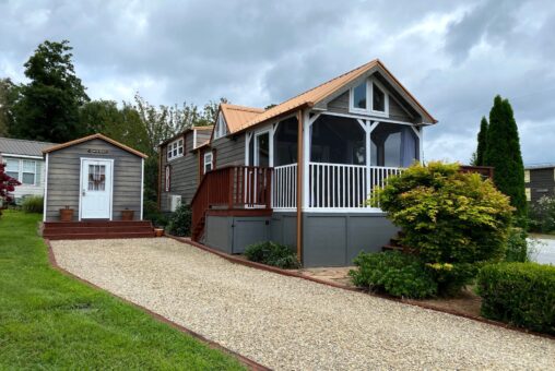 A tiny house with a screened porch and shed sits by a gravel drive at 40 Drifting Brook Lane under a cloudy sky.