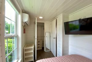 Bright, small bedroom at 40 Drifting Brook Lane with white walls, a wall-mounted TV, and a window overlooking greenery.