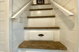 Carpeted stairs with white walls, a drawer in the step, and a LOVE RULE sign at 40 Drifting Brook Lane real estate.