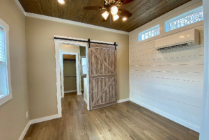 Bedroom with view on slidding farmhouse door leading to bathroom