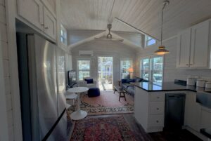 A bright, cozy living room and kitchen at 49 Skipping Stone Lane with white walls, large windows, and modern furniture.