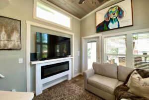 Cozy living room on Just Wandering Lane with a couch, wall-mounted TV, and colorful dog artwork above the door.