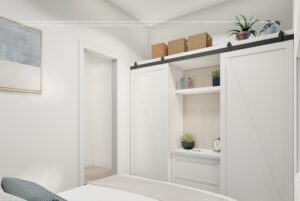 White sliding barn doors reveal a built-in closet with shelves, storage boxes, and decor in a bright bedroom.