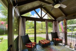 Screened patio on Just Wandering Lane with two chairs, ottoman, ceiling fan, and views of pond and trees.