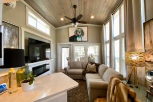 Bright, cozy living room on Just Wandering Lane with large windows, neutral sofas, and colorful dog artwork above the couch.