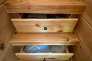 Three partially open wooden drawers at Just Wandering Lane reveal various items stored inside.