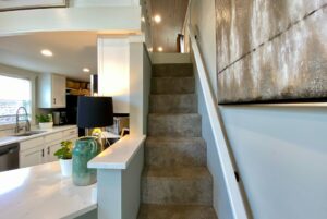 Carpeted staircase in a modern kitchen with white cabinets on Just Wandering Lane, marble counters, and accents.