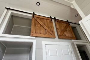 Two wooden sliding barn doors on a track above white double closet doors at 124 Misty Knoll Way.