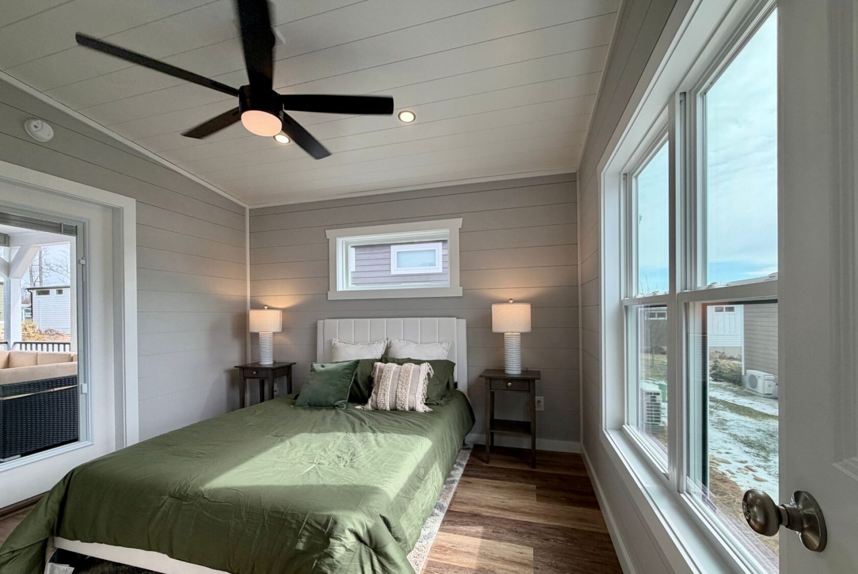 Bedroom at 124 Misty Knoll Way with green bedding, large windows, ceiling fan, and bedside tables with lamps.
