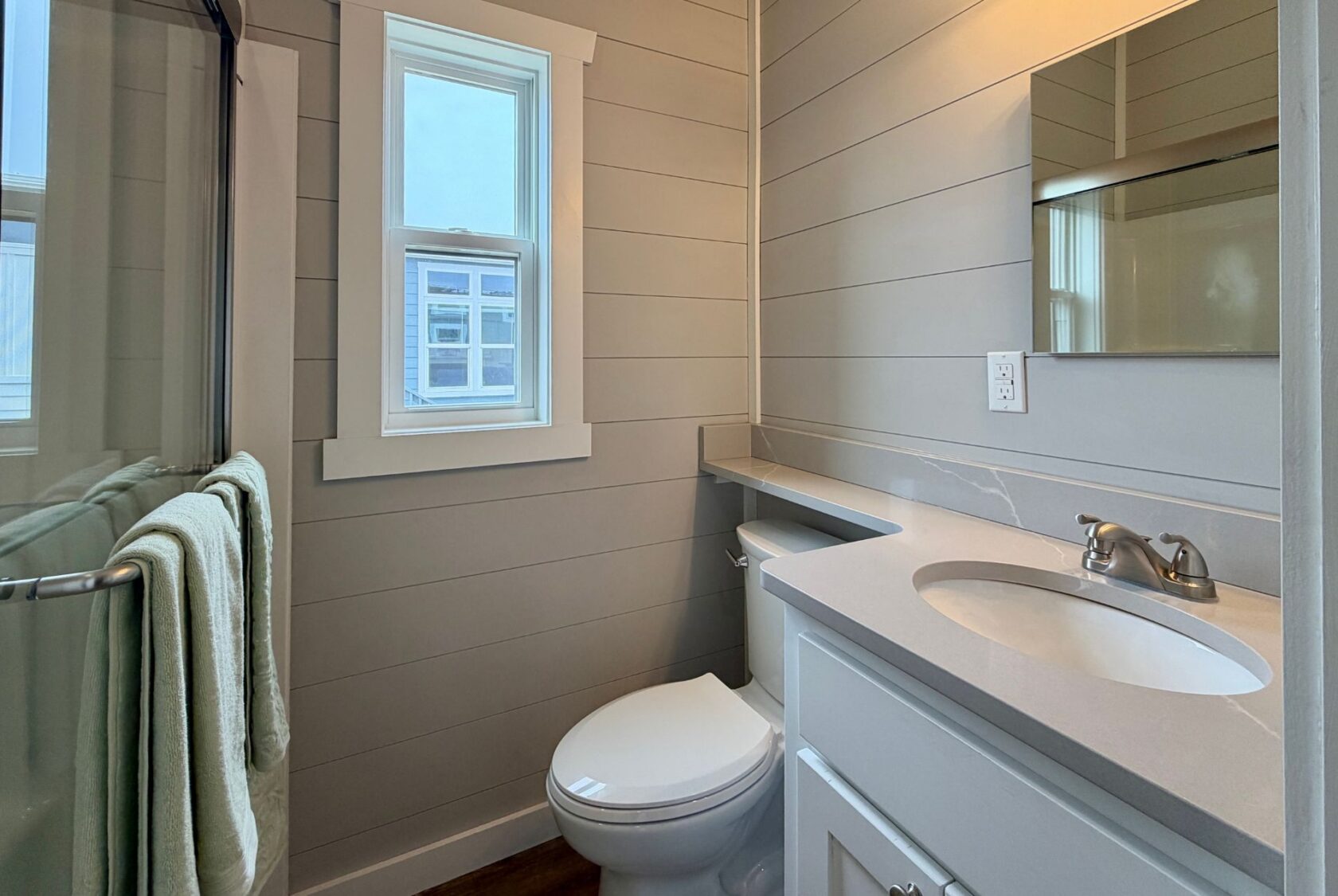 Small modern bathroom at 124 Misty Knoll Way with gray walls, a toilet, sink, mirror, and window above a towel rack.