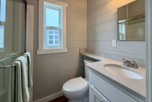 Small modern bathroom at 124 Misty Knoll Way with gray walls, a toilet, sink, mirror, and window above a towel rack.