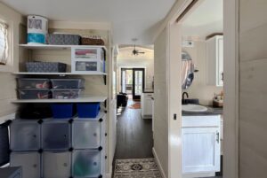 View of a hallway in a tidy Two Swans Lane home, with storage bins left, bathroom right, and living room ahead.