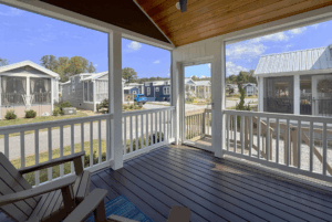 View from a covered porch with chairs, overlooking Skipping Stone Lane lined with small modern cottages.