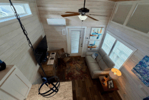 Cozy living room at Skipping Stone Lane with sofa, TV, colorful rug, wall art, and ceiling fan viewed from above.