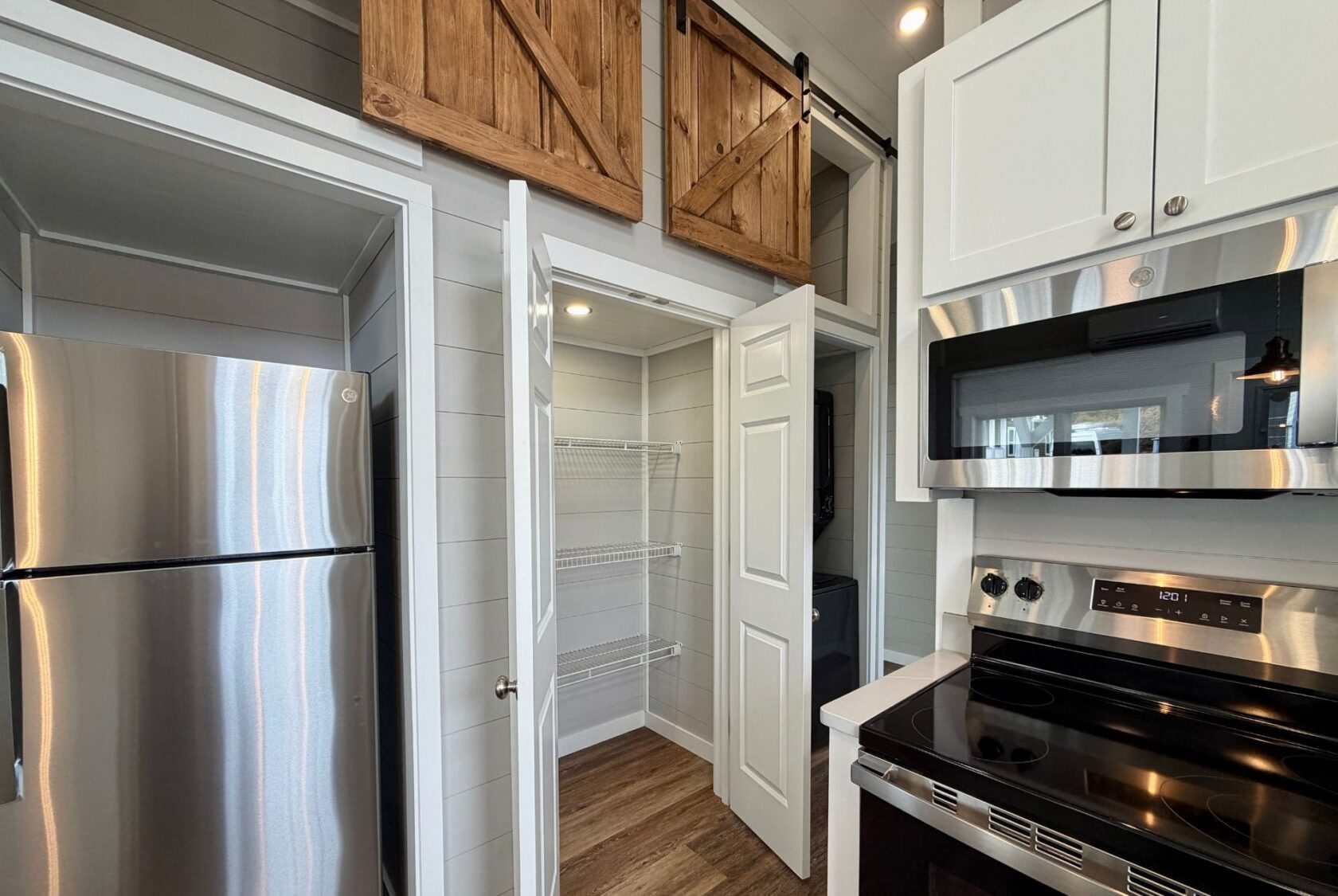 Modern kitchen at 124 Misty Knoll Way features stainless appliances, open pantry shelves, and wooden barn doors above.