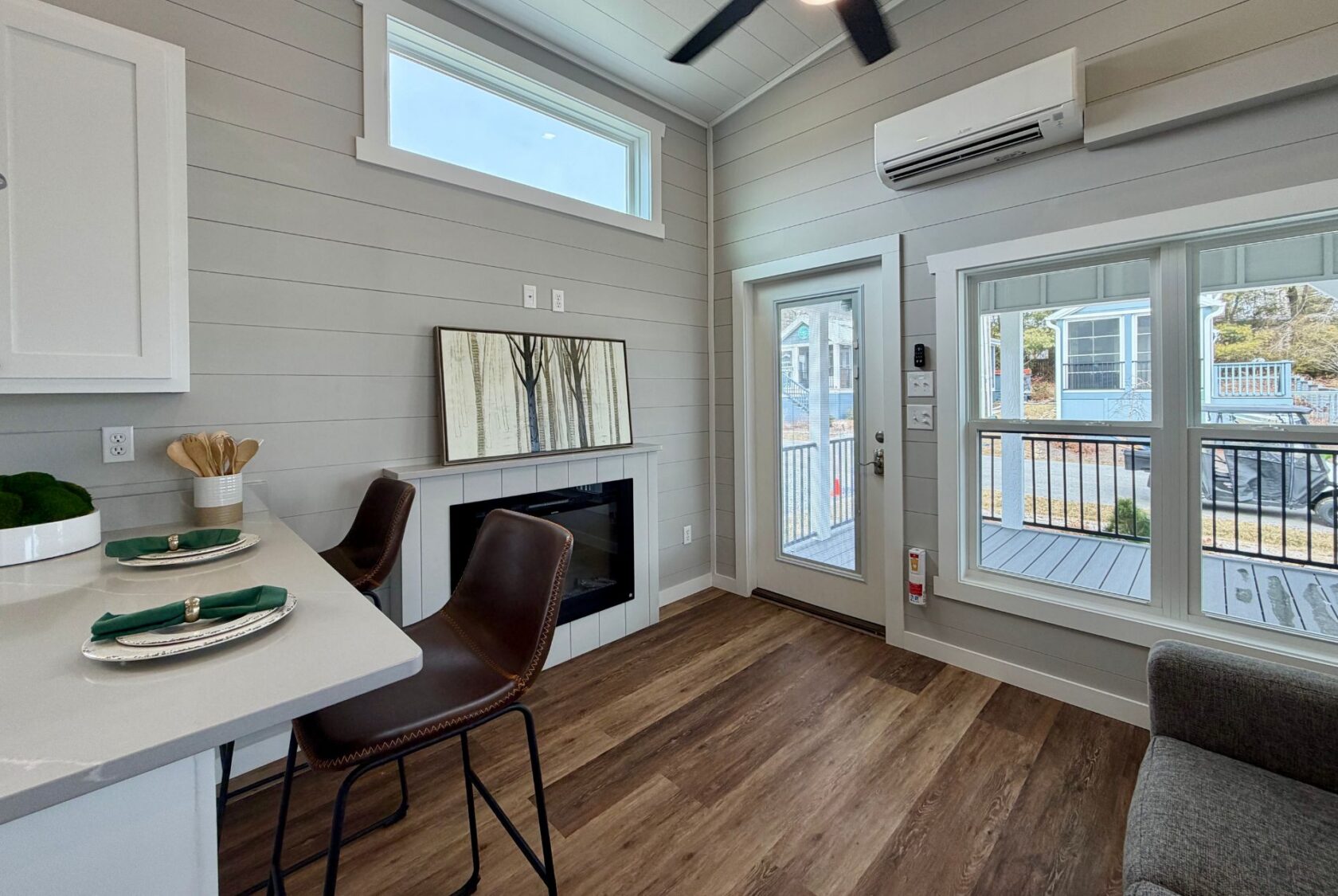 Modern living space at 124 Misty Knoll Way with wood floors, bar stools, large windows, and porch access.